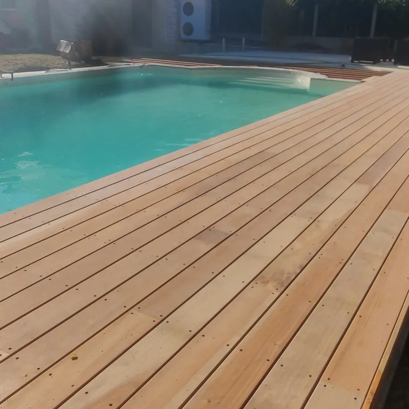 Terrasse en lames de bois blondes autour d'une table ronde, vues depuis un angle montrant le grain du bois et la jonction